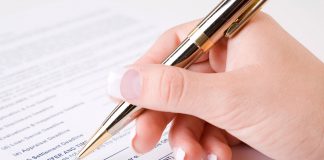 Sold: How to Go From Listing to Closing When Selling Your Manufactured Home A hand signing a document with a ballpoint pen.