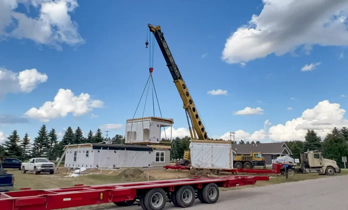 Photo of a modular home being installed on a foundation.